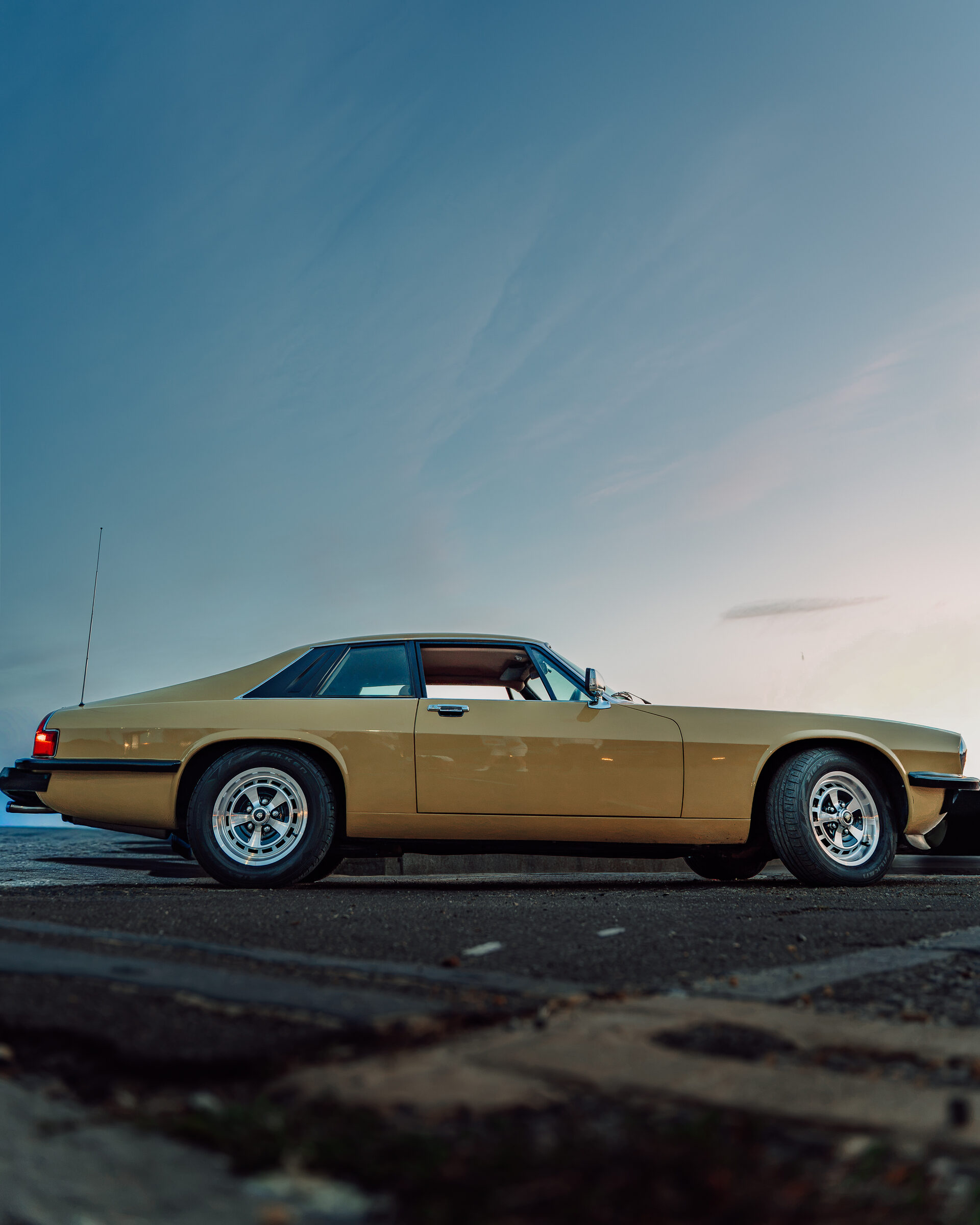 Classic gold Jaguar XJS side profile at dusk