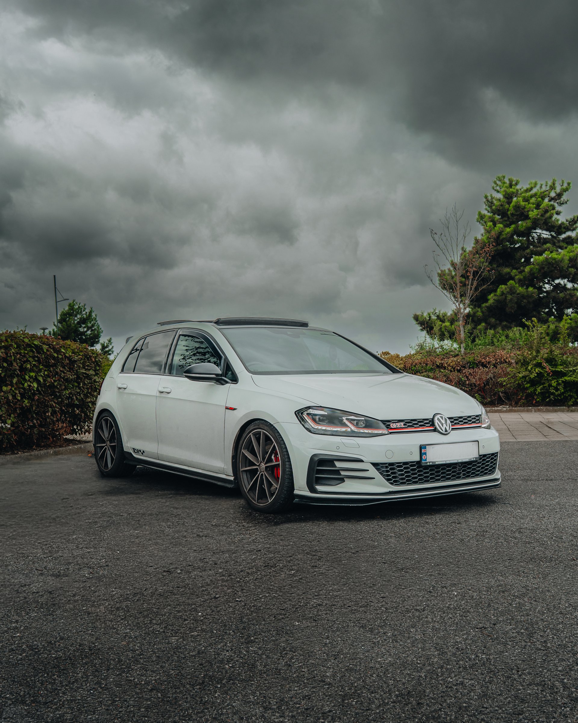 White Volkswagen Golf GTI parked under a stormy sky